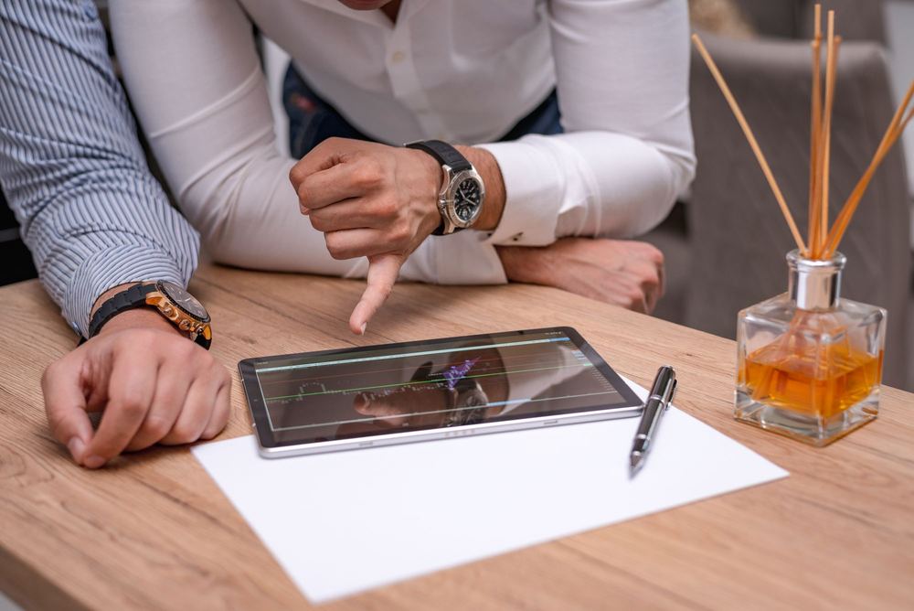 Mãos acompanhando indicadores em gráfico num tablet sobre a mesa